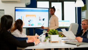 Black woman worker explaning company statistics in front of colleagues
